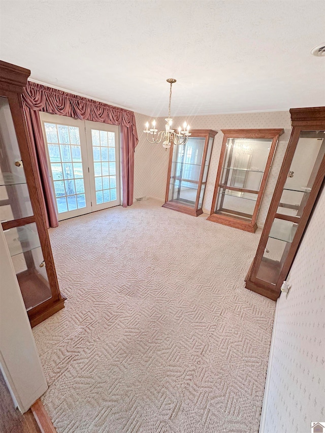 interior space featuring carpet floors, a textured ceiling, and an inviting chandelier