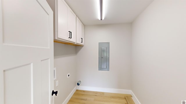 washroom with electric dryer hookup, light hardwood / wood-style floors, cabinets, and electric panel