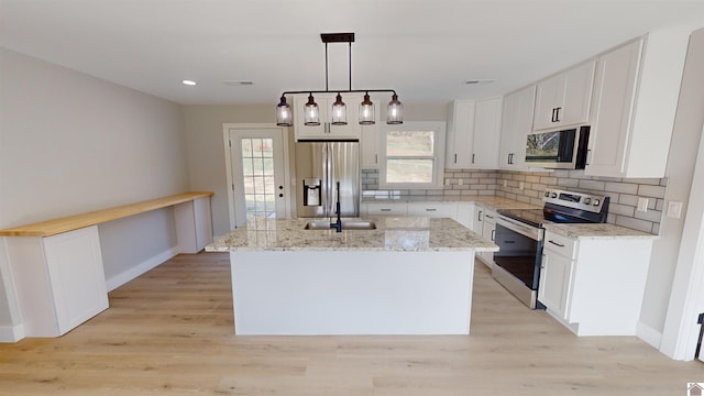 kitchen featuring pendant lighting, white cabinets, light hardwood / wood-style floors, appliances with stainless steel finishes, and a kitchen island