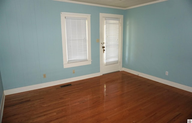 empty room featuring ornamental molding and dark wood-type flooring