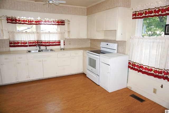 kitchen with a wealth of natural light, electric range, sink, and white cabinets