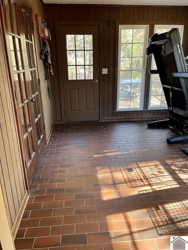 doorway with a wealth of natural light and wooden walls