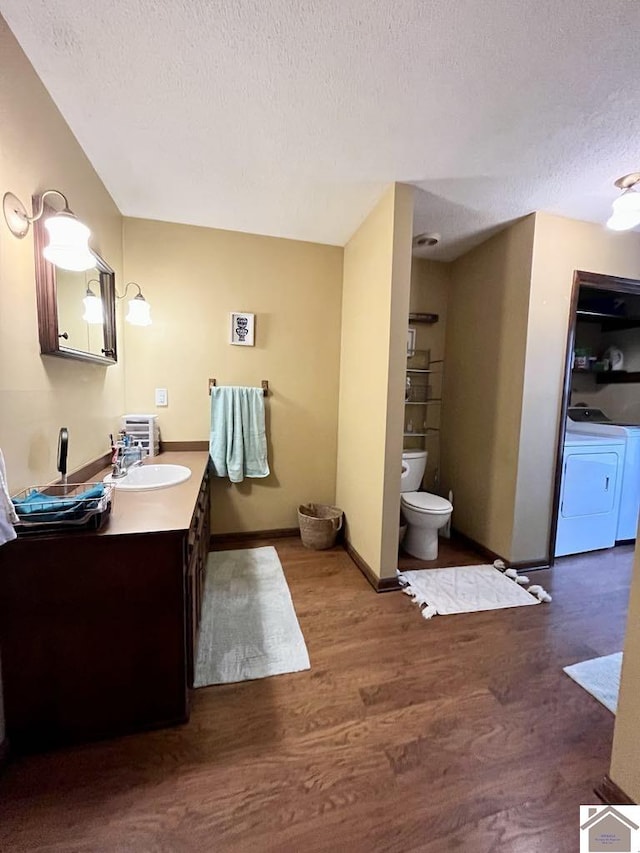 bathroom featuring vanity, a textured ceiling, washing machine and clothes dryer, hardwood / wood-style floors, and toilet