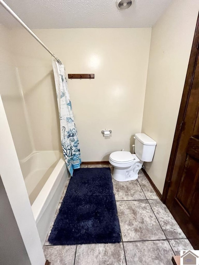 bathroom with tile patterned floors, shower / bath combination with curtain, toilet, and a textured ceiling