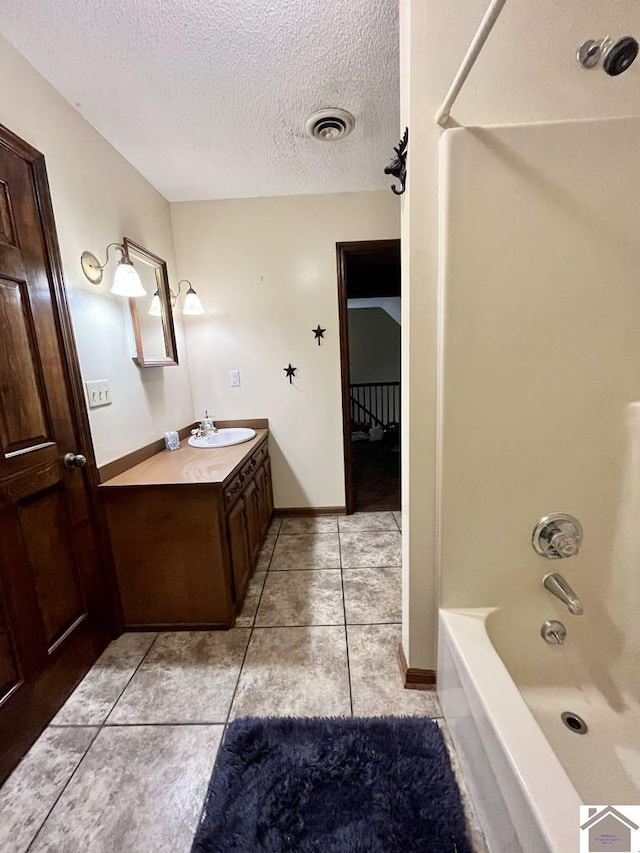 bathroom featuring tile patterned floors, shower / bathing tub combination, vanity, and a textured ceiling