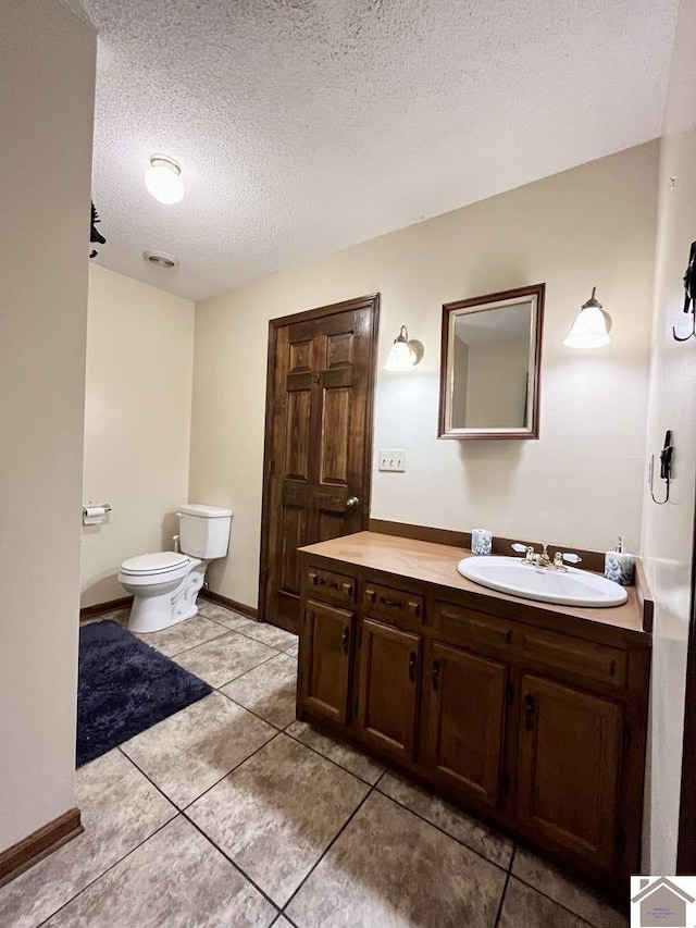 bathroom with tile patterned floors, vanity, a textured ceiling, and toilet