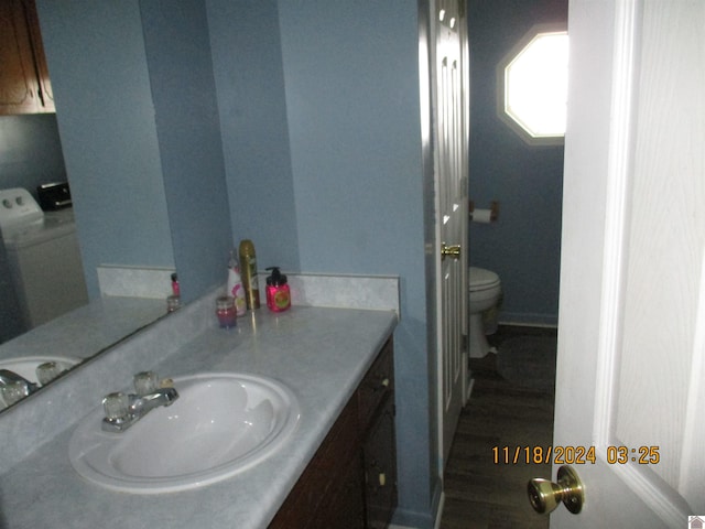 bathroom with toilet, washer / dryer, wood-type flooring, and vanity