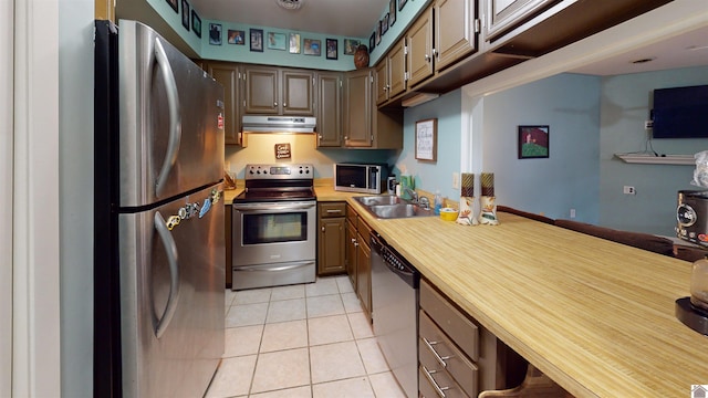 kitchen featuring butcher block counters, sink, light tile patterned floors, and appliances with stainless steel finishes