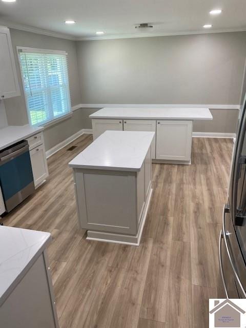 kitchen featuring white cabinets, stainless steel appliances, a kitchen island, and light hardwood / wood-style floors