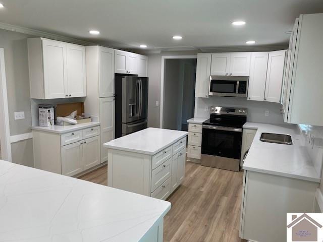 kitchen featuring a center island, appliances with stainless steel finishes, crown molding, white cabinets, and light wood-type flooring