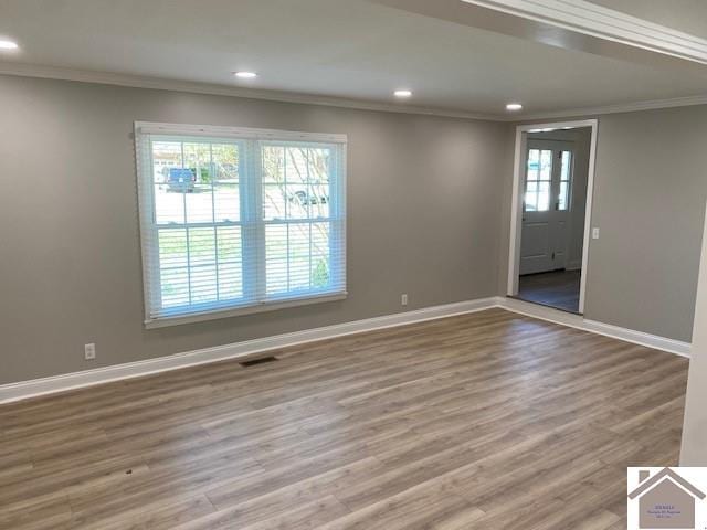 empty room with hardwood / wood-style floors, a healthy amount of sunlight, and ornamental molding