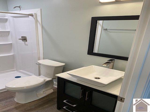 bathroom featuring a shower, vanity, wood-type flooring, and toilet