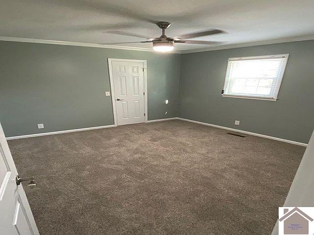 unfurnished room with ceiling fan, dark carpet, and ornamental molding