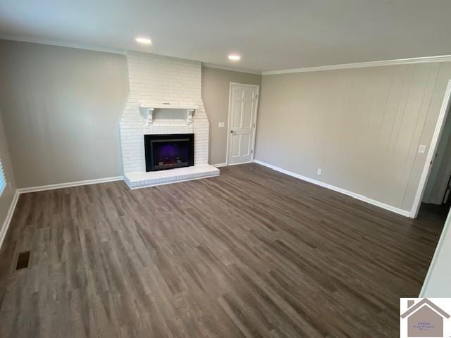 unfurnished living room featuring dark hardwood / wood-style flooring, ornamental molding, and a brick fireplace