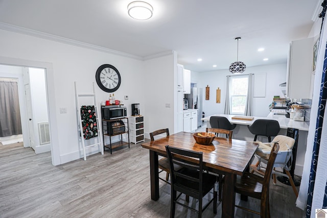 dining space featuring light wood-type flooring and ornamental molding