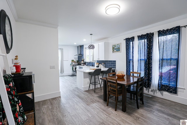 dining space featuring light hardwood / wood-style floors, crown molding, and sink