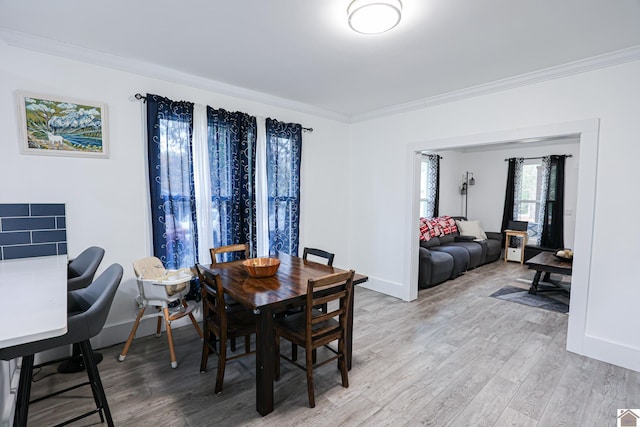 dining space featuring light wood-type flooring and crown molding