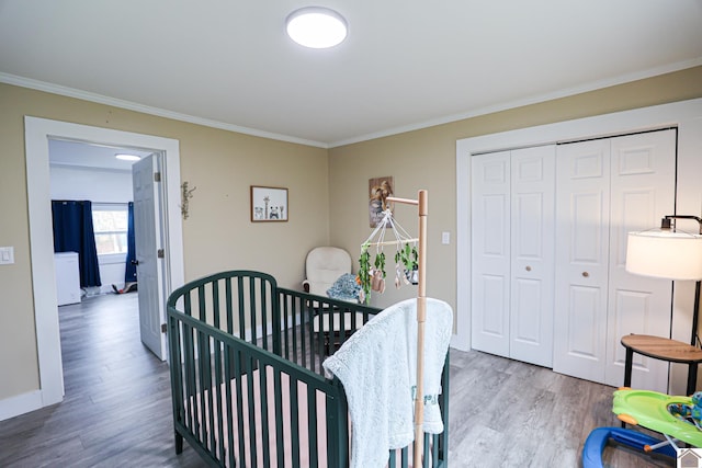 bedroom featuring a closet, ornamental molding, a crib, and hardwood / wood-style flooring