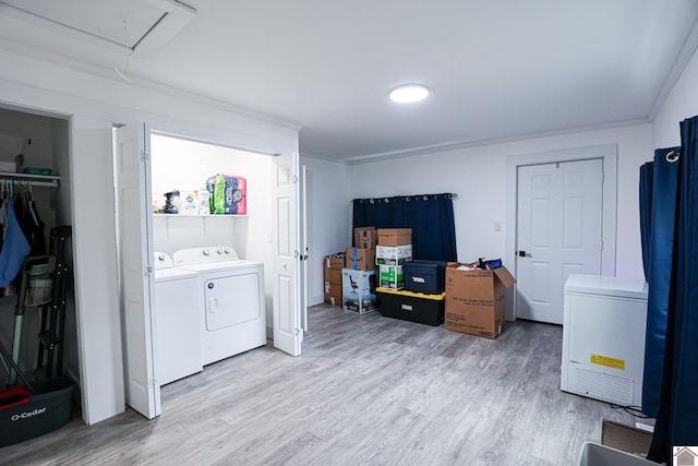 laundry room featuring washer and clothes dryer, light hardwood / wood-style floors, and crown molding