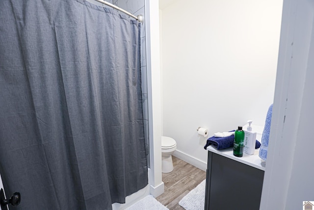 bathroom featuring hardwood / wood-style floors, a shower with curtain, and toilet