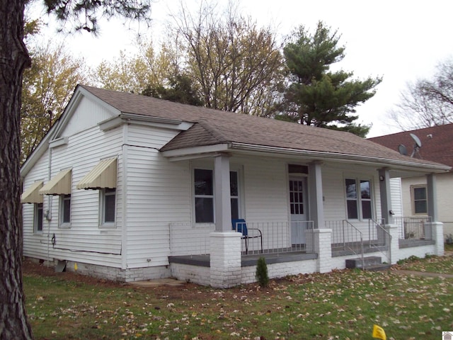 bungalow with covered porch and a front lawn