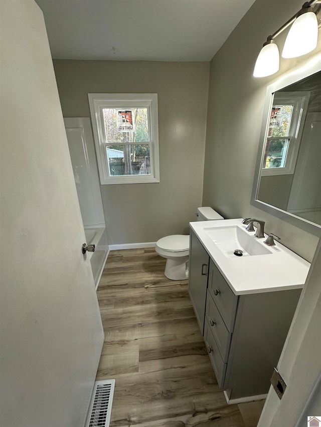 full bathroom featuring hardwood / wood-style flooring, plenty of natural light, toilet, and vanity