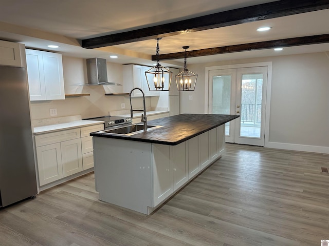 kitchen featuring white cabinetry, decorative light fixtures, stainless steel appliances, and wall chimney range hood