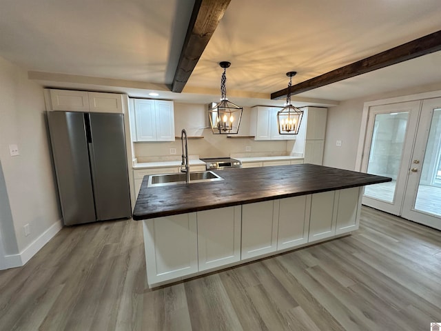 kitchen with white cabinets, beam ceiling, butcher block counters, and appliances with stainless steel finishes