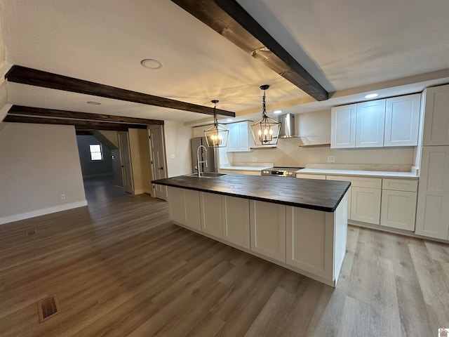 kitchen featuring wood counters, pendant lighting, light hardwood / wood-style flooring, beamed ceiling, and white cabinets