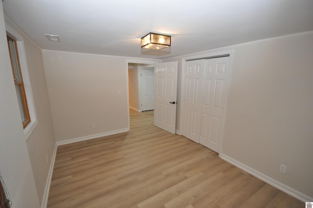 unfurnished bedroom featuring a closet, ornamental molding, and light hardwood / wood-style flooring