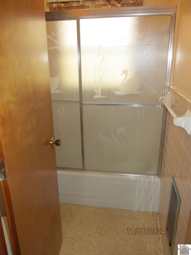 bathroom featuring enclosed tub / shower combo and tile walls