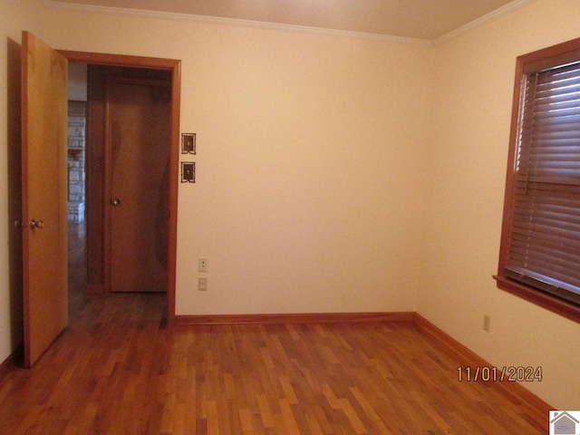 spare room with hardwood / wood-style flooring and crown molding