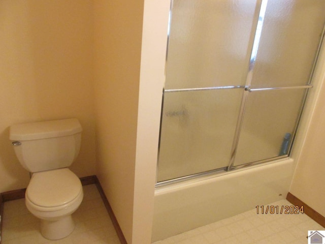 bathroom featuring toilet and combined bath / shower with glass door