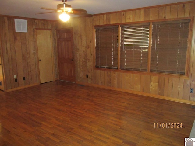 empty room featuring wood walls, ceiling fan, wood-type flooring, and ornamental molding