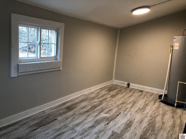 unfurnished room featuring wood-type flooring and gas water heater