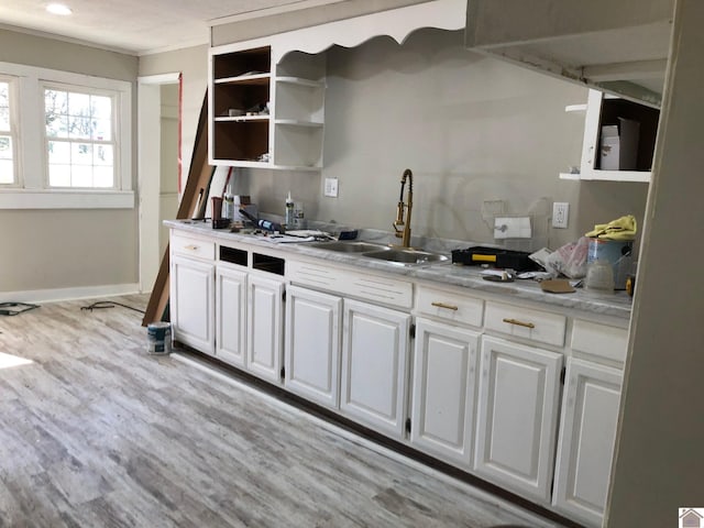 kitchen with white cabinets, crown molding, sink, and light hardwood / wood-style flooring