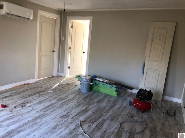 interior space with a wall mounted AC, crown molding, and hardwood / wood-style flooring