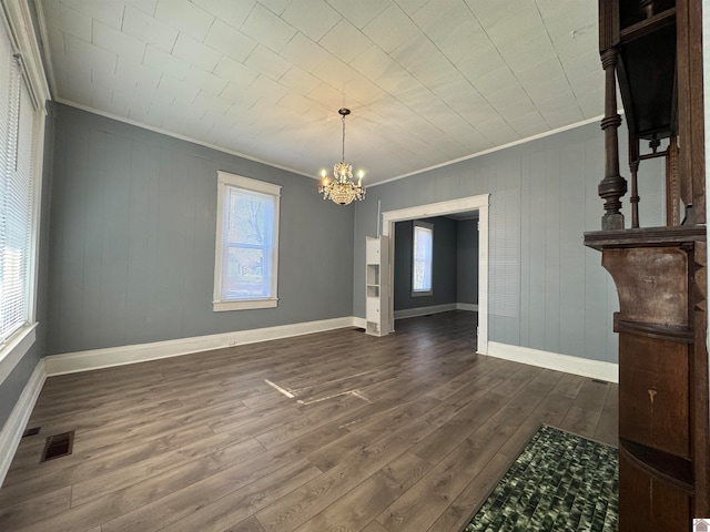 unfurnished dining area featuring a notable chandelier, dark hardwood / wood-style flooring, and crown molding