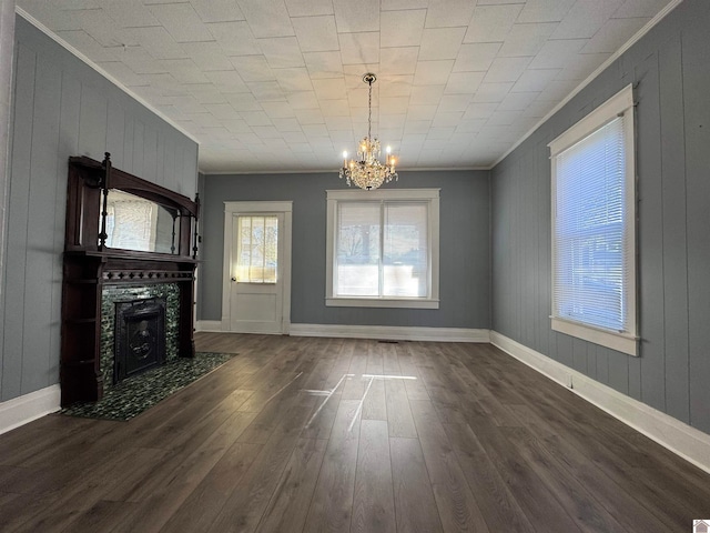 unfurnished living room featuring crown molding, dark wood-type flooring, and an inviting chandelier