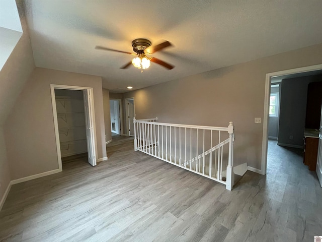 bonus room with a textured ceiling, light wood-type flooring, and ceiling fan