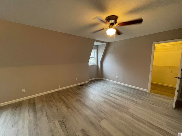 bonus room featuring a textured ceiling, light hardwood / wood-style flooring, ceiling fan, and lofted ceiling