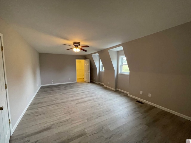 bonus room with light wood-type flooring, vaulted ceiling, and ceiling fan