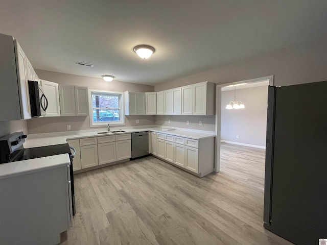 kitchen with appliances with stainless steel finishes, light wood-type flooring, white cabinetry, and a notable chandelier