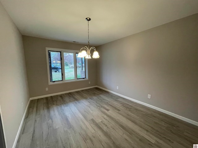 unfurnished dining area featuring a chandelier and wood-type flooring