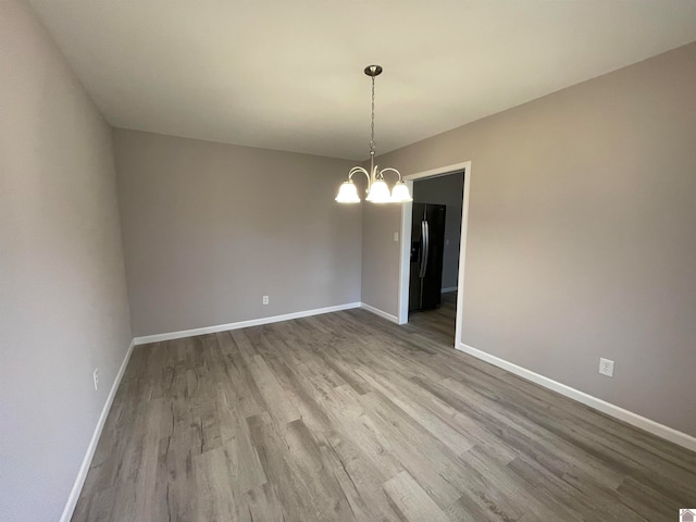 unfurnished room featuring wood-type flooring and a notable chandelier