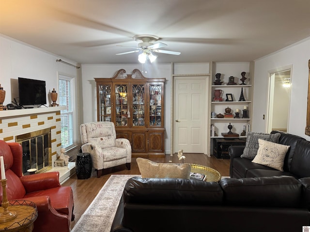 living room featuring a fireplace, hardwood / wood-style flooring, ceiling fan, and crown molding