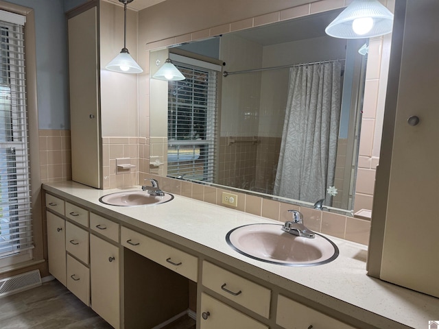 bathroom with hardwood / wood-style floors, vanity, walk in shower, and tasteful backsplash