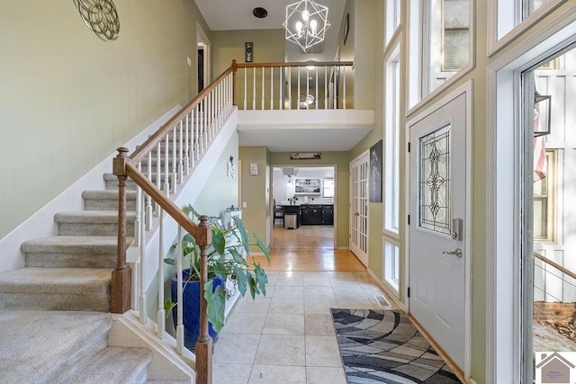 foyer entrance with a chandelier, a towering ceiling, light hardwood / wood-style flooring, and a healthy amount of sunlight