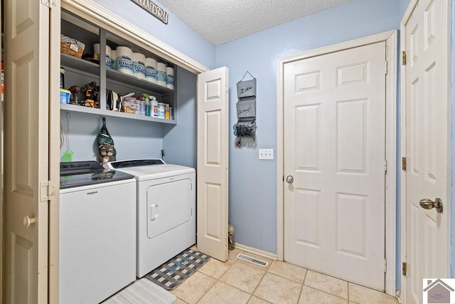 washroom featuring independent washer and dryer, a textured ceiling, and light tile patterned flooring