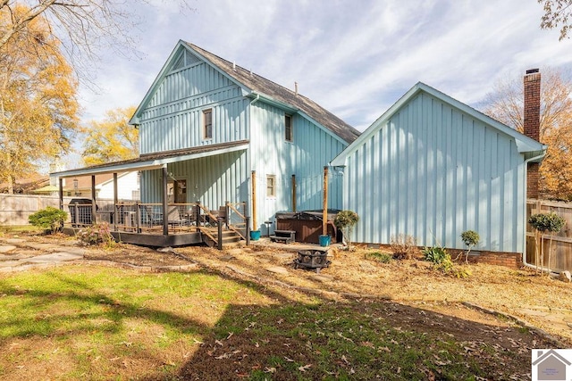 rear view of house with a deck, a yard, and a hot tub